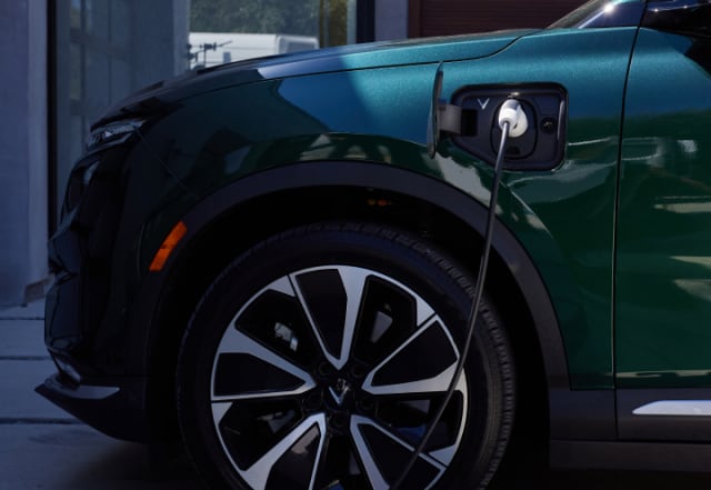 Green VinFast SUV plugged in to charge