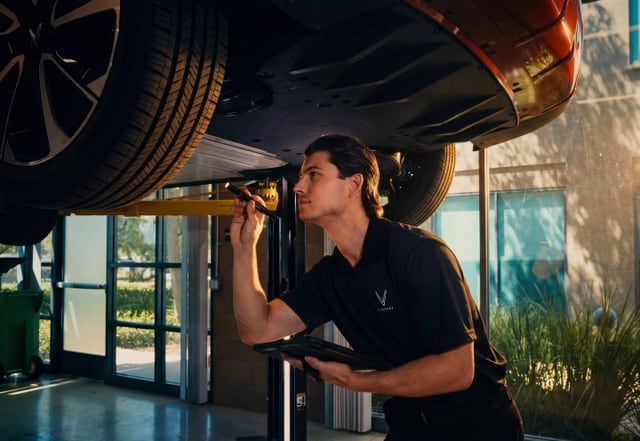 VinFast technician inspecting the underside of a vehicle on a lift